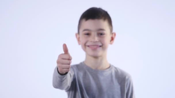 Smiling boy holding his thumb up isolated on the white background — Stock Video