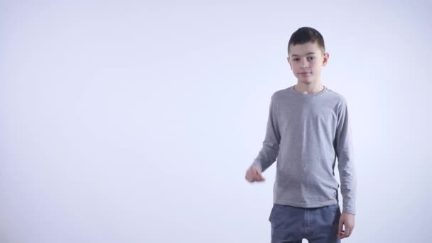 Un niño sonriente muestra su dedo a un lado sobre el fondo blanco — Vídeo de stock