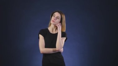 Karanlık bir arka plan üzerinde bir şey düşünmeye ciddi genç kadın