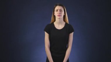 Sevimli genç bir beyaz kadın kameraya bir siyah arka plan üzerinde görünüyor.