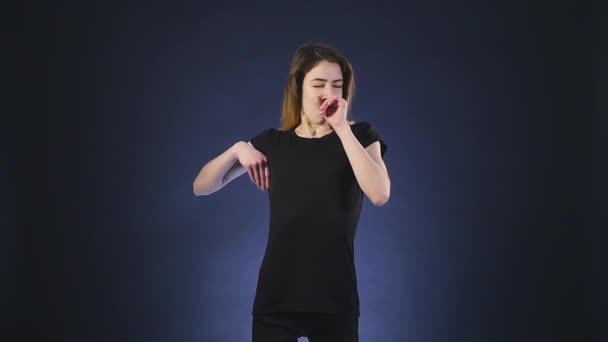 Jeune femme aux cheveux longs fatiguée et bâillant, isolée sur un fond sombre — Video