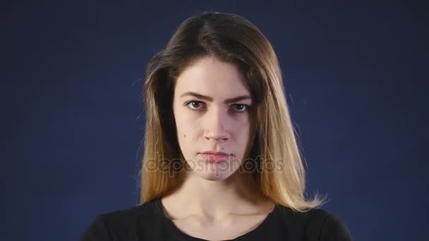 Een jong meisje met een boos gezicht donkere achtergrond — Stockvideo