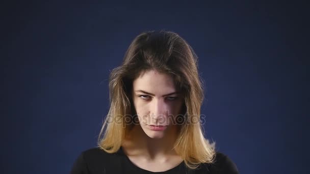 Een jong meisje met een boos gezicht donkere achtergrond — Stockvideo
