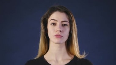 Sevimli genç bir beyaz kadın kameraya bir siyah arka plan üzerinde görünüyor.