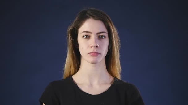 A cute young white woman looks into the camera on a black background — Stock Video