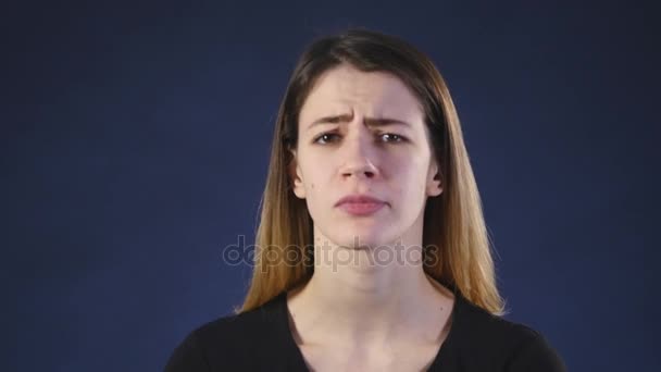 Una linda mujer blanca joven mira a la cámara sobre un fondo negro — Vídeo de stock