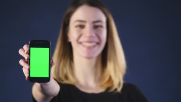 Skupić się na telefon komórkowy. Młoda kobieta ręce, pokazując ekran smartphone puste na białym tle na zielonym tle i wskazując na ekranie — Wideo stockowe