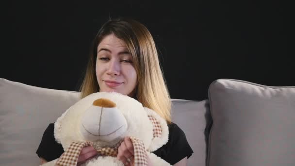 Vrij lachende vrouw zittend op de Bank knuffelen teddybeer — Stockvideo