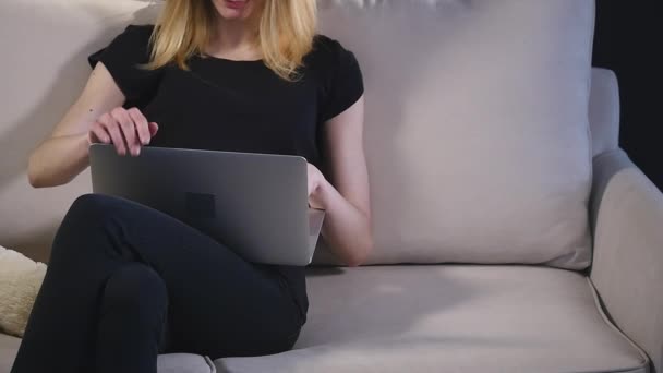 Ragazza con un computer portatile sul divano. sfondo nero — Video Stock