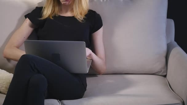 Κορίτσι με ένα laptop στον καναπέ. μαύρο φόντο — Αρχείο Βίντεο