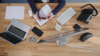 yüksek açılı görünüş onun Ofis Masası belgelerle ve dizüstü çalışan genç bir esmer. PaperWork üzerinde çalışan iş kadını