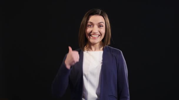 Впевнена молода бізнес-леді дає великі пальці на чорному тлі — стокове відео