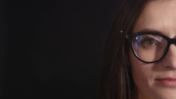 Jovem mulher profissional bonita removendo seus óculos no fundo preto — Vídeo de Stock