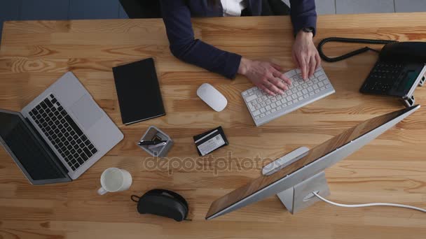 Blick aus der Vogelperspektive auf eine junge Brünette, die an ihrem Bürotisch mit Dokumenten und Laptop arbeitet. Geschäftsfrau arbeitet an Papierkram — Stockvideo