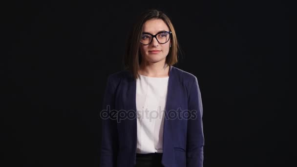 Schöne Geschäftsfrau mit Brille posiert vor schwarzem Hintergrund — Stockvideo