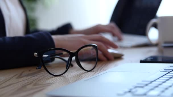 Σκηνή γραφείο με σημειώσεις και έγγραφα, ένα στυλό και ένα ζευγάρι γυαλιά. Μια νεαρή γυναικεία χέρια εργάζονται για το laptop και τις σημειώσεις σε ένα σημειωματάριο — Αρχείο Βίντεο