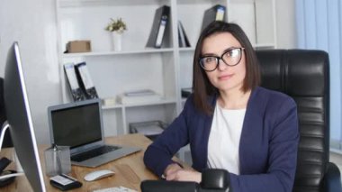 Kamera ve gülümseme bakarak ofisinde çalışan başarılı iş kadın