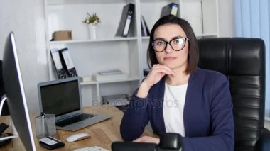 Kamera ve gülümseme bakarak ofisinde çalışan başarılı iş kadın