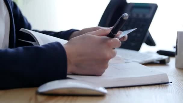 Close up de uma mulher mão escrevendo em uma agenda em uma mesa em casa ou escritório — Vídeo de Stock