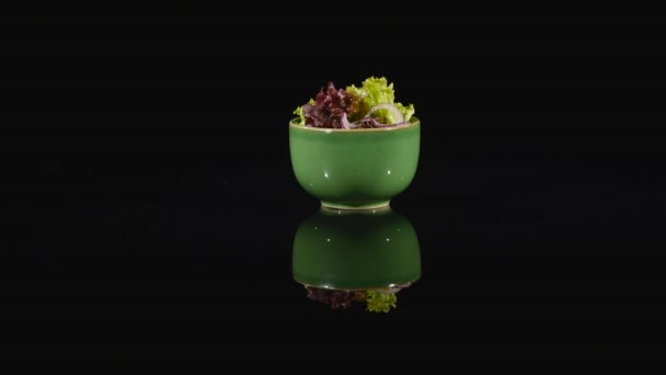 Salada verde fresca em um prato verde em fundo preto — Vídeo de Stock