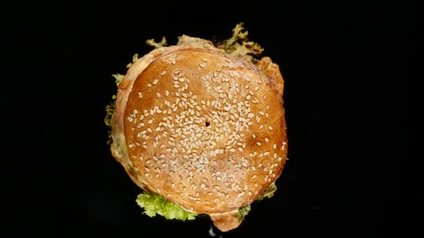 Hamburguesa fresca y apetitosa girando sobre fondo negro. Disparo loopable sin costura, 4k — Vídeo de stock