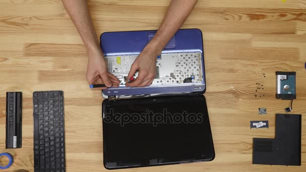 Мужчина-инженер ремонтирует ноутбук. Вид сверху на деревянный стол — стоковое видео