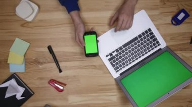 Android telefon ve laptop hangi döşeme üzerinde ahşap masa evde kullanma. Üstten Görünüm. Nedensel bir yaşam tarzı. Yeşil ekran