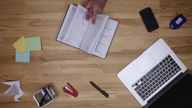 Adam üstünde laptop türleri ve notlar aşağı yazıyor. Ofiste çalışan serbest meslek. İş adamı ve bilgisayar