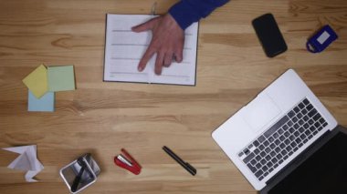 Adam üstünde laptop türleri ve notlar aşağı yazıyor. Ofiste çalışan serbest meslek. İş adamı ve bilgisayar