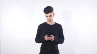 Gülümseyen genç adam akıllı telefonuna bakarken mesaj beyaz arka planda izole edilmiş.