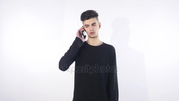 Desconcertado joven confundido hablando con el teléfono celular. Hombre retrato pensando y hablando por teléfono — Vídeos de Stock