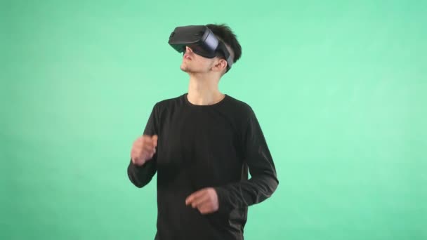 Unge mann som bruker virtuelle briller mot grønn bakgrunn – stockvideo