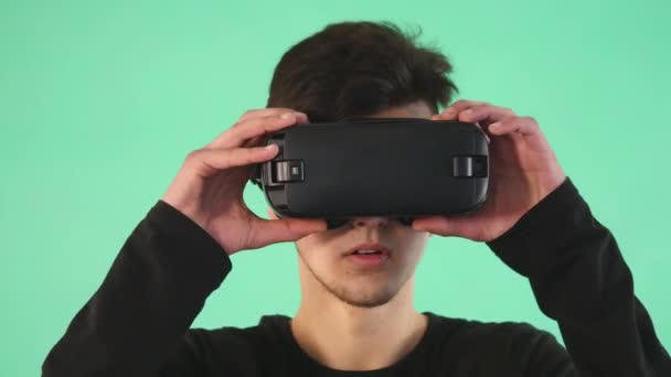 Jovem usando óculos virtuais contra fundo verde — Vídeo de Stock