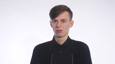 Beyaz arka plan üzerinde duran ve iğrenme yüzünde gösterilen yakışıklı delikanlı
