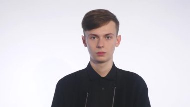 Beyaz arka plan üzerinde duran ve iğrenme yüzünde gösterilen yakışıklı delikanlı