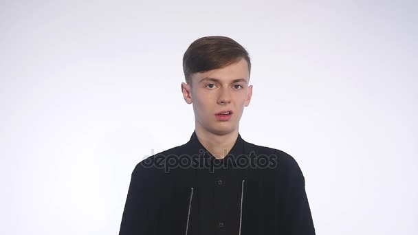 Stilig ung man står mot vit bakgrund och visar avsky på hans ansikte — Stockvideo