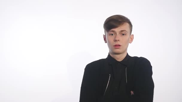 Handsome young man standing against white background and showing disgust on his face — Stock Video