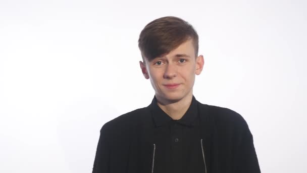 Shy young handsome man smiling, looking at camera over white background — Stock Video