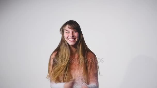 Молодих красивих кавказьких дівчина розмахував волосся і посміхається на білому тлі в slowmotion — стокове відео
