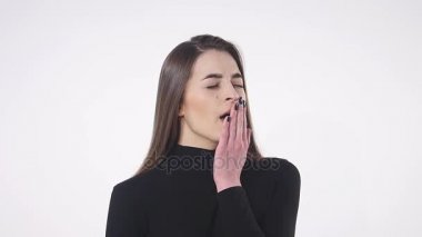 Güzel kadın beyaz arka planda can sıkıntısından esniyor.