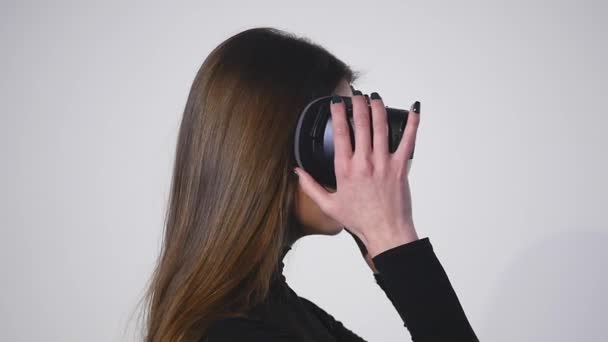 La mujer usa una pantalla montada en la cabeza. Una mujer en una máscara de realidad virtual mira alrededor — Vídeo de stock