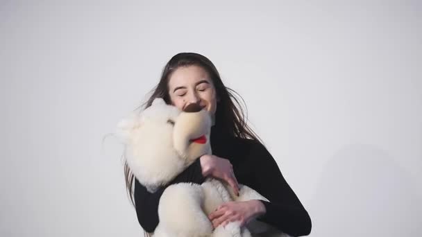 Jeune femme attrape un ours en peluche sur un fond blanc — Video