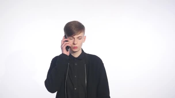 Спантеличений спантеличений молодий чоловік розмовляє з мобільним телефоном. — стокове відео