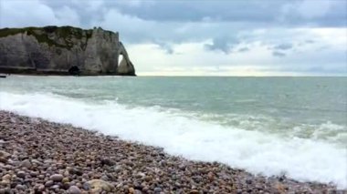 Dalgalar bir rock bulutlu gökyüzü backdround in yakınındaki taş bir plajda