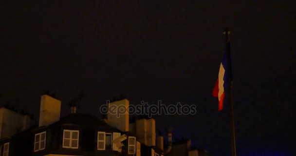 Bandeira francesa acenando ao vento perto de casa no fundo do céu noturno — Vídeo de Stock