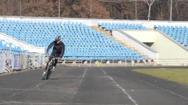 Ritratto dell'uomo in sella a una bici da corsa su una pista. modello dotato di un ingranaggio professionale per bici, utilizza bici da corsa professionale — Video Stock