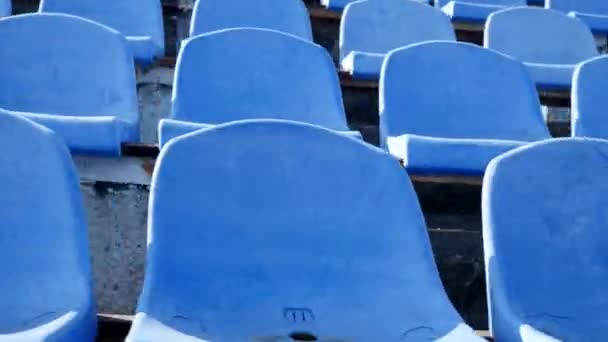 blaue Plastiksitze im Stadion, Kamera schiebt sich nach links. Abstrakt