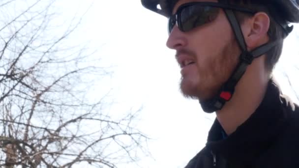 Närbild porträtt av allvarliga och eftertänksamma ryttare med stubb bär cykling kläder, skyddande hjälm och glasögon — Stockvideo