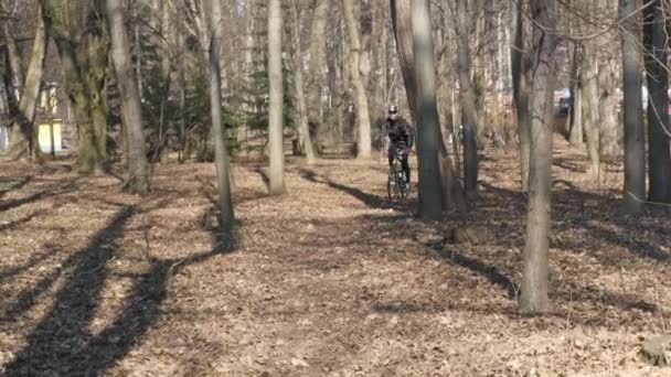 Тропинка пугает осенними листьями, человек проезжает мимо на велосипеде — стоковое видео