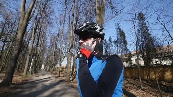 Professional cyclist speaks by phone in park — Stock Video